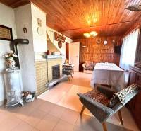 The interior of a wooden cabin with a fireplace, a sofa, and decorative flowers.