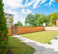 A landscaped garden with a lawn and a wooden fence at a 2-room apartment.