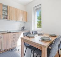 A kitchen in a 2-room apartment with wooden cabinets and a dining table.