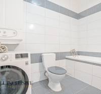 Bathroom in a 2-room apartment with a shower, washing machine, and toilet, bright tiles.