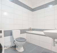 Bathroom with a bathtub, washing machine, and toilet in a 2-room apartment.