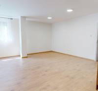 A spacious room with a wooden floor and a kitchen area in a 2-room apartment.
