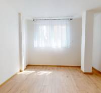 A room with a light wooden floor and white curtains in a two-room apartment.