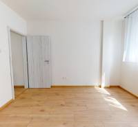 A bright room in a two-room apartment with parquet flooring and light-colored doors.