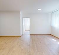 A bright room in a 2-room apartment with wooden flooring and a built-in kitchen.