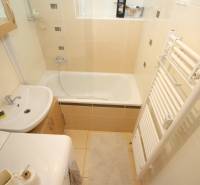 Compact bathroom with a bathtub, sink, and washing machine in a 2-room apartment.