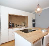 A kitchen with an island, pendant light, stove, and appliances in a two-room apartment.