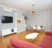 Living room in a 2-room apartment with a red sofa and a dining table for four.