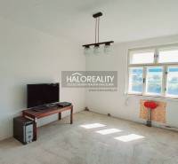 A room in a family house with a window, a table, a television, and a computer.
