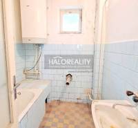 A bathroom in a family house with blue tiles, a bathtub, and a sink.