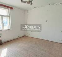 A room in a family house with a wooden floor and cracks on the walls.