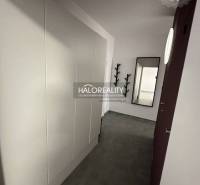 Purple kitchen unit and large wall clock in a studio apartment.