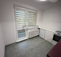Kitchen area of a studio apartment with pink cabinets and a stove.