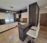 A kitchen in a 4-room apartment with white cabinets, bright lighting, and a bar counter.