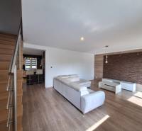 4-room apartment with a wooden staircase, white couch, and dark wall cladding.