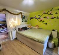 A bedroom in a family house with a colored wall and decoration, connected to the living room.