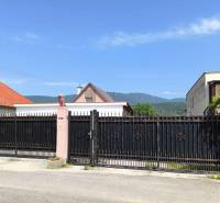 A family house in Nitrica with a large wrought-iron gate and a beautiful mountain backdrop.
