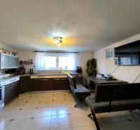 A kitchen with a kitchen unit, table, benches, and a television in a family house.