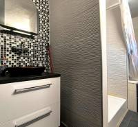 A bathroom with a tiled sink and shower in a family house.