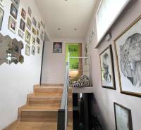 A staircase in a family house with many paintings on the walls.