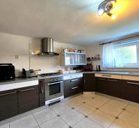A kitchen in a family house with dark lower cabinets, appliances, tiled floor.