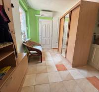 A hallway with furniture and tiles, light walls, and air conditioning in a family house.