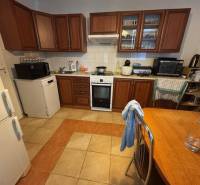 A kitchen in a family house with wooden cabinets, a stove, and a refrigerator.