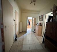 A hallway of a family house with a tiled floor and wooden furniture.