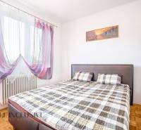 A bedroom in a family house with a bed, curtains, and a built-in wardrobe.