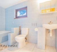 A bathroom in a family house with a bathtub, toilet, and sink. Light blue tiles.