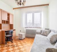 A room with a desk, sofa, and wooden furniture in a family house.
