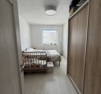 Bedroom in a 2-room apartment with a wooden bed, wardrobe, and window with daylight.