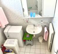 A bathroom with a sink, washing machine, toilet, and white tiles in commercial premises.