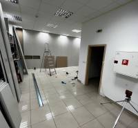 Interior of commercial premises with a ladder, tiles, and lighting during renovation.