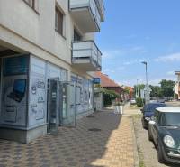 A building with commercial spaces on Štúrova Street in Senec, next to parked cars.
