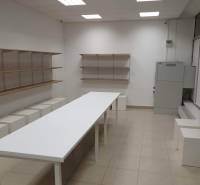 White table, shelves, tiles, commercial spaces with lighting and installed ceiling panels.