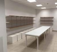 Commercial space with a long table, shelves, and white cubes on the floor.