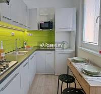 A kitchen in a studio apartment with green tiles and a dining table for two people.