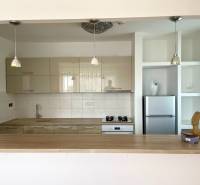 A kitchen with a wooden countertop, a bar counter, and built-in cabinets in a 2-room apartment.