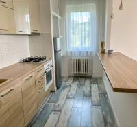 A kitchen in a 2-room apartment with built-in appliances, a wooden countertop, and a light floor.