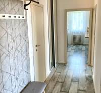 A hallway in a 2-room apartment with a bench, a coat rack, and a built-in wardrobe.