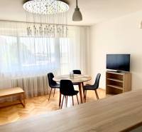 2-bedroom apartment with wooden flooring, dining table, TV, and modern lighting.