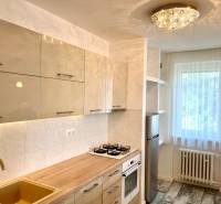 A kitchen in a 2-room apartment with modern cabinets, a gas stove, and a bright window.
