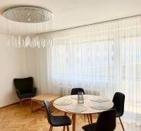 Dining area with a round table and curtains in a 2-room apartment, with an elegant chandelier.