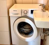 Samsung washing machine next to a compact sink in the bathroom of a 2-room apartment.