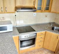 A kitchen unit in a studio apartment with a microwave, a cooktop, and a sink.