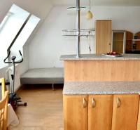 Kitchen corner in a studio apartment with a bed, table, and exercise equipment.