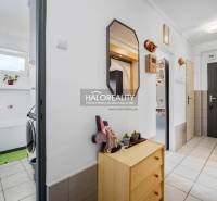 A hallway in a 2-room apartment with a coat rack, mirror, and bathroom on the left side.