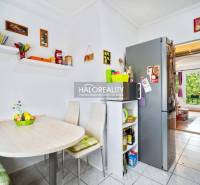 Dining area in a basement 2-room apartment with a kitchen and a view into the living room.