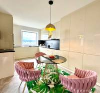 Dining area with a glass table and pink chairs in a 3-room apartment.